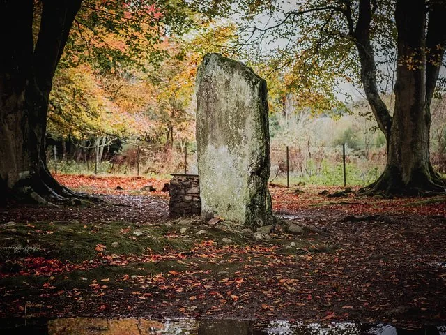 Tall standing stone at Clava Cairns surrounded by autumn leaves on the ground