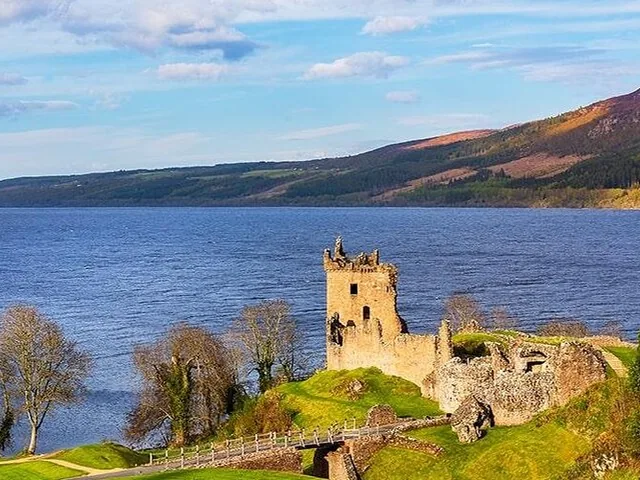 Ruins of Urquhart Castle on the shore of Loch Ness under a blue sky