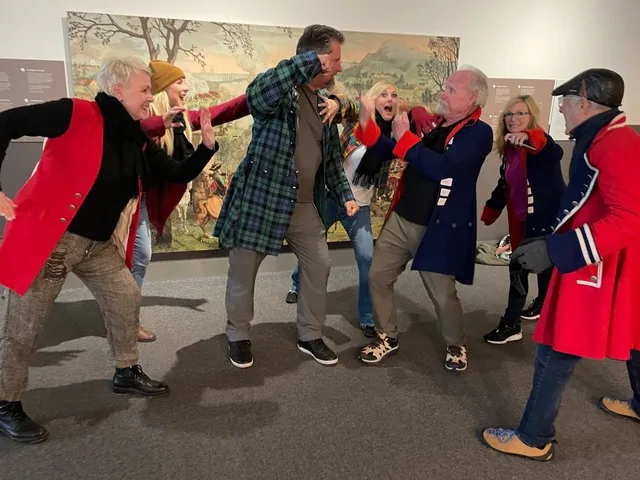 Group of people in historical costumes posing playfully at a Culloden exhibition