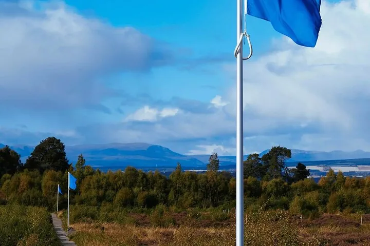 Blue flags flying along a path at Culloden Battlefield with mountains in the distance