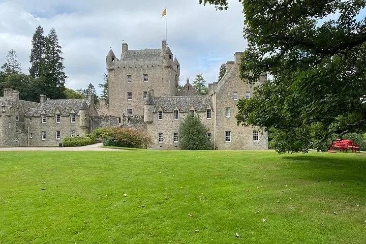 Large Scottish castle, likely Cawdor Castle, with a sprawling green lawn